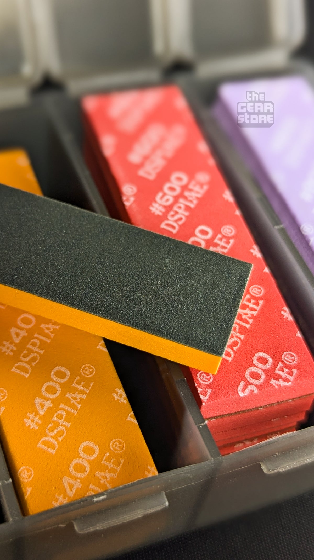 A DSPIAE #400 sanding sponge flipped to show its black abrasive face on the orange foam backing