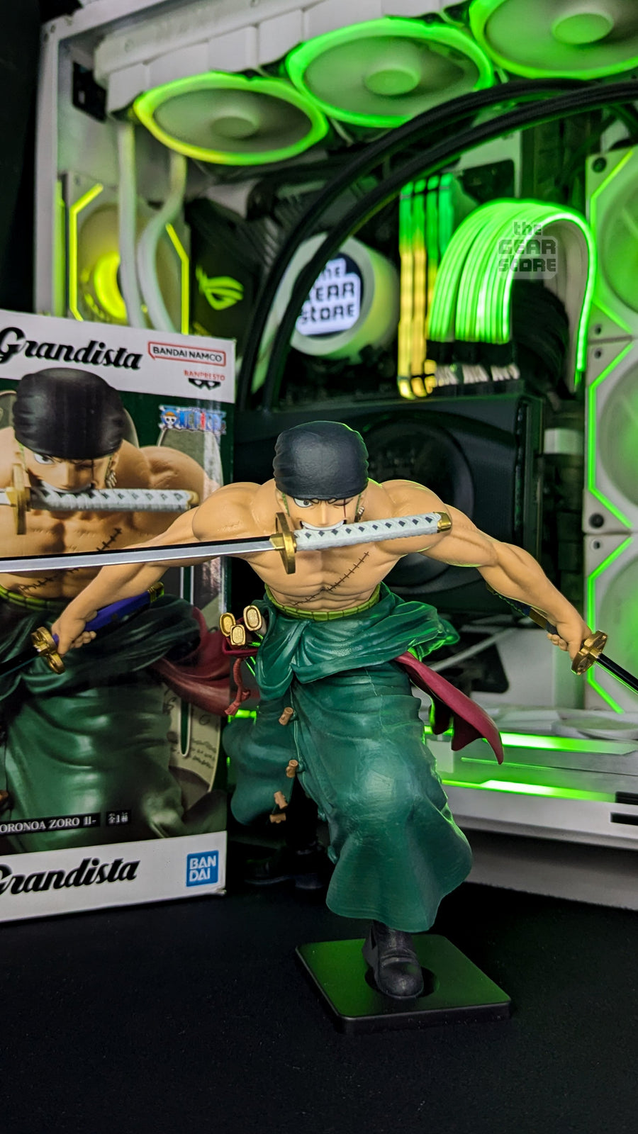 A Roronoa Zoro figure with drawn swords on The GEAR Store's desk, the RGB-lit PC behind it