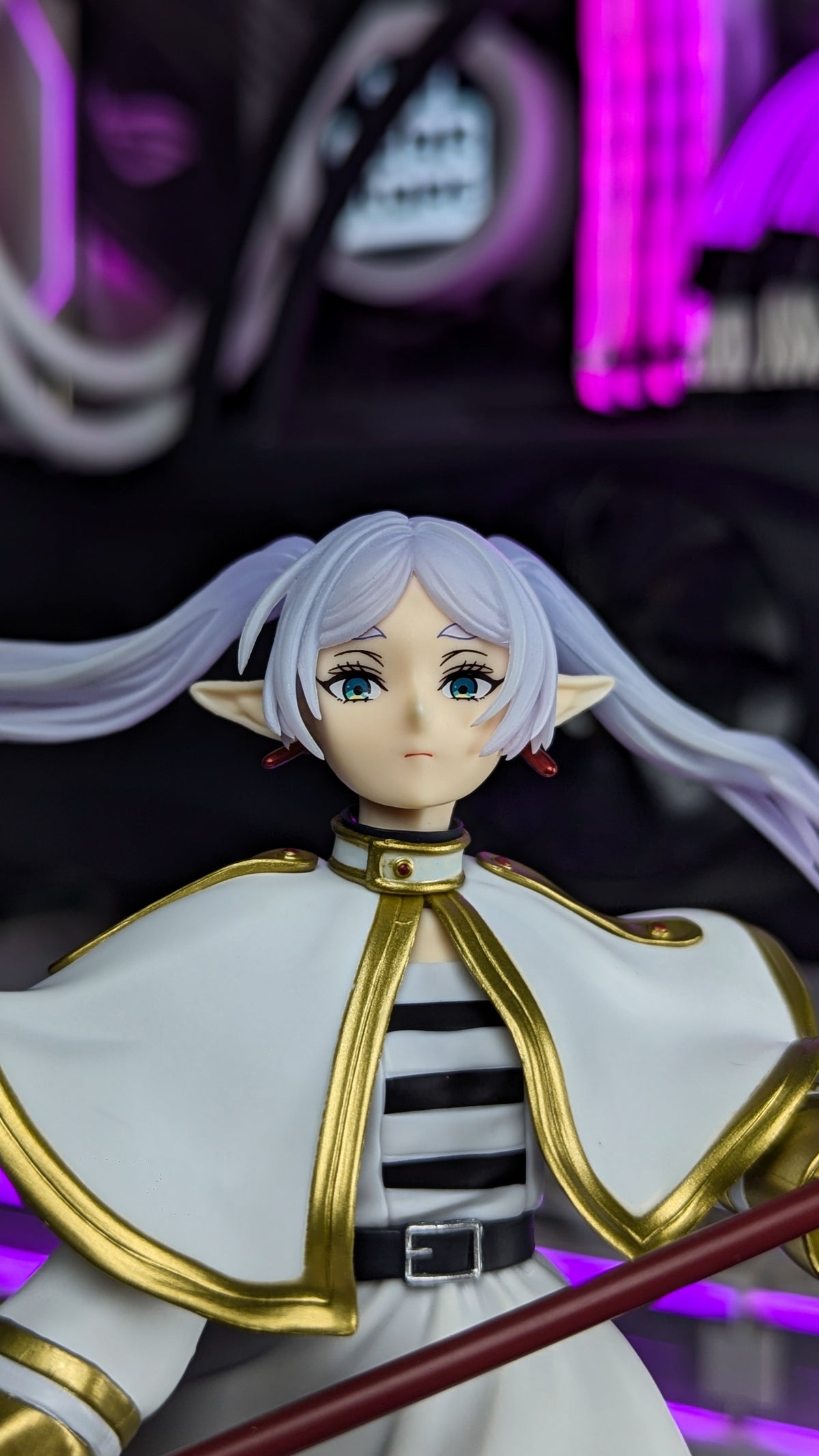 Close-up of Frieren's face, pointed ears and gold-trimmed collar