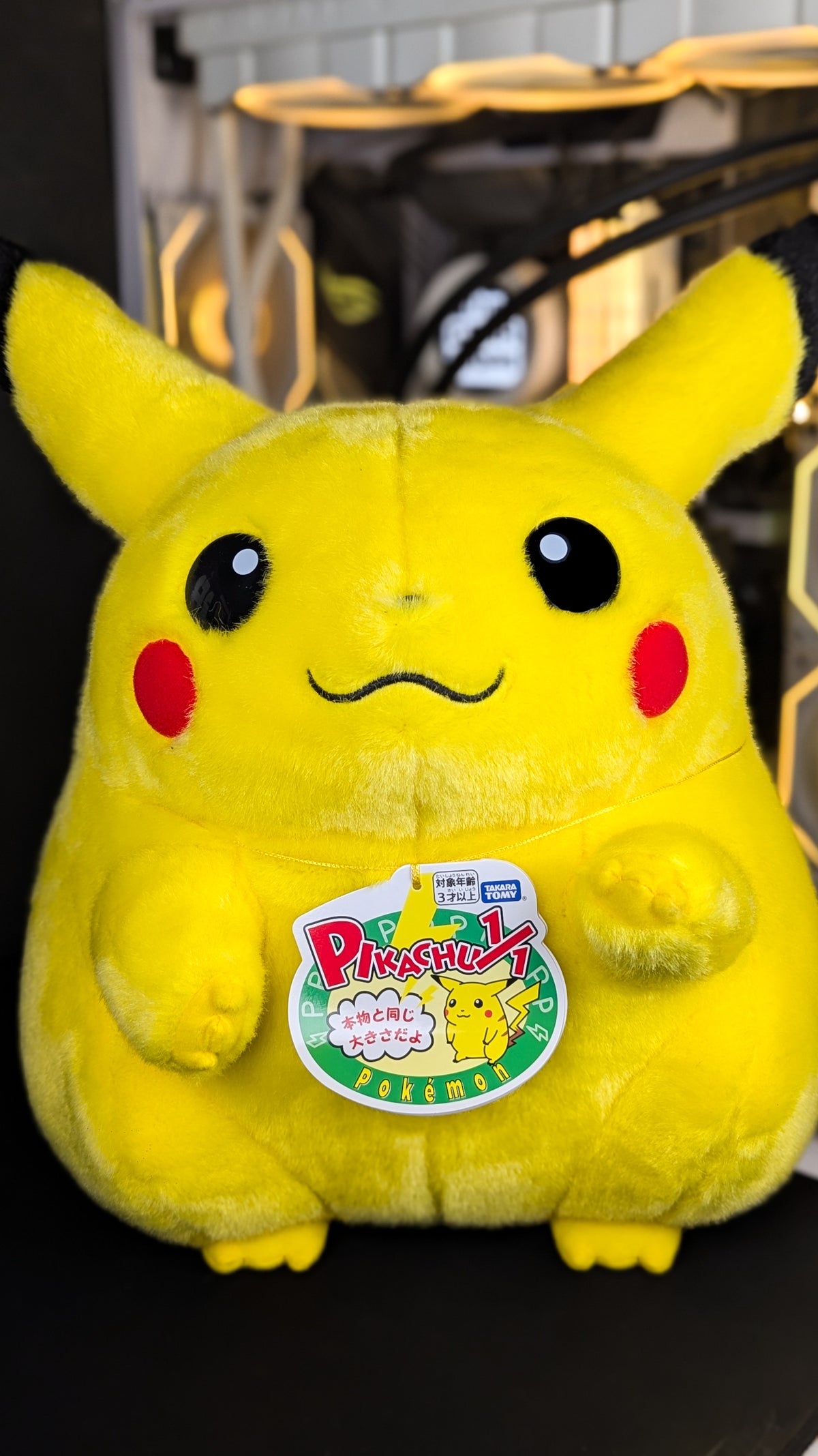 Welcome Back! Pikachu 1/1 life-size plush shown full length from the front with its Takara Tomy hang tag attached